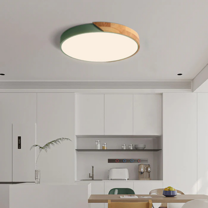 Plafonnier à coque verte et bois clair allumé au-dessus d'une cuisine blanche épurée 3
