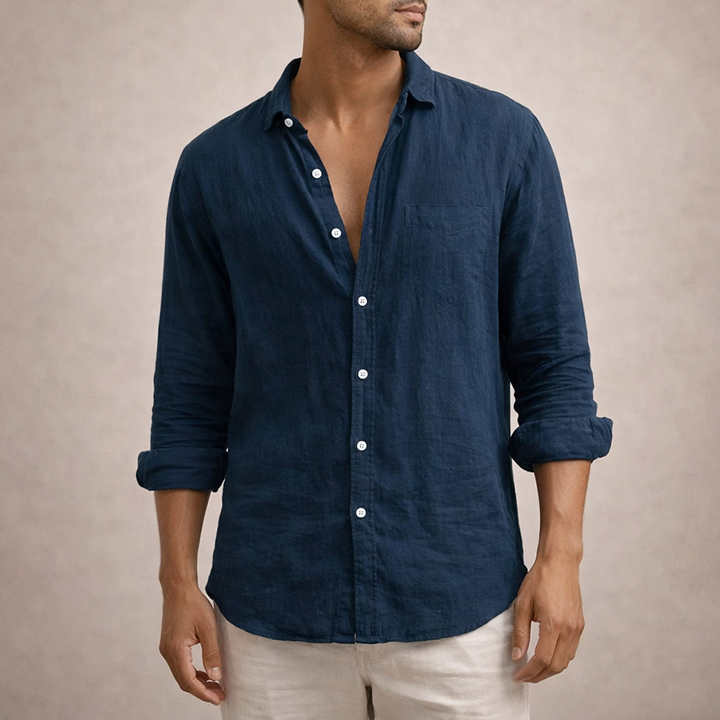 Chemise en lin bleu marine avec poche poitrine, portée de face, col ouvert, manches retroussées et pantalon clair. 7
