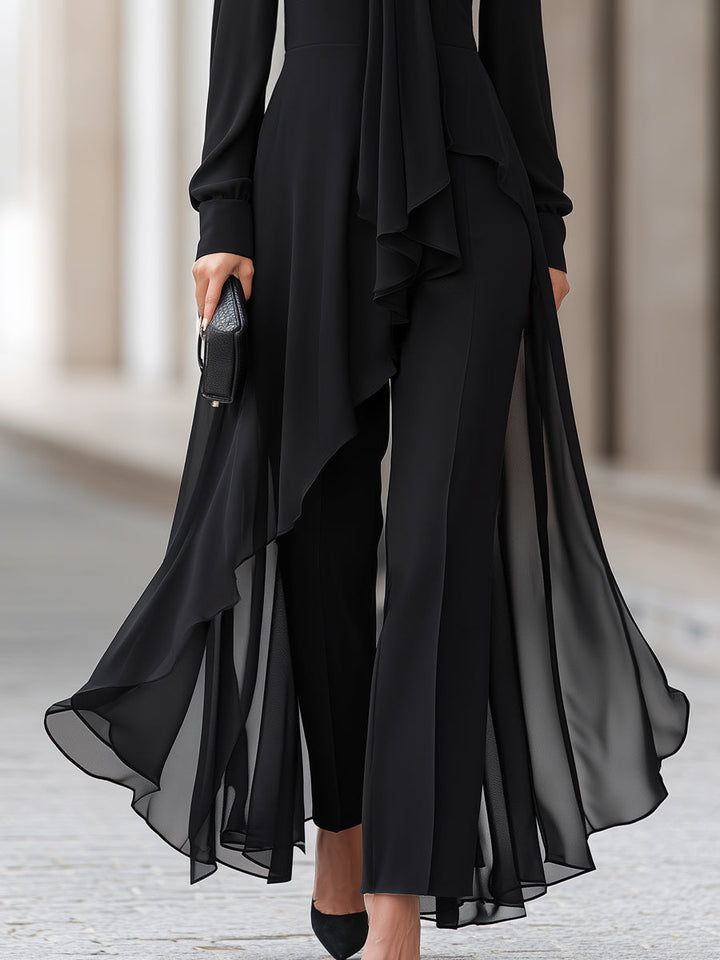 Détail du bas de la tenue : pan de mousseline noire asymétrique et transparent flottant sur un pantalon évasé, avec escarpins noirs. 4