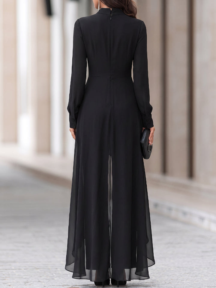 Vue de dos de la tenue noire : fermeture à glissière centrale, manches longues boutonnées aux poignets et pans de mousseline translucides sur le pantalon. 5