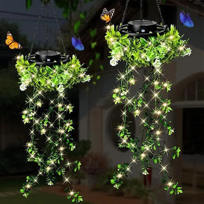 Deux suspensions solaires de lierre illuminées dans un jardin la nuit, avec petites fleurs blanches et papillons colorés autour. 4