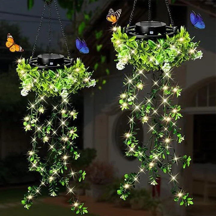 Deux suspensions solaires de lierre illuminées dans un jardin la nuit, avec petites fleurs blanches et papillons colorés autour. 4
