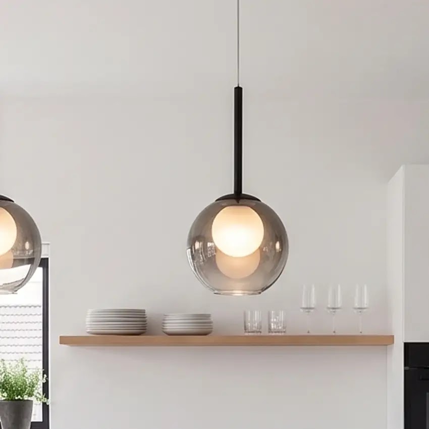 Gros plan sur une suspension globe gris fumé allumée au-dessus d'une étagère en bois garnie d'assiettes et de verres 11
