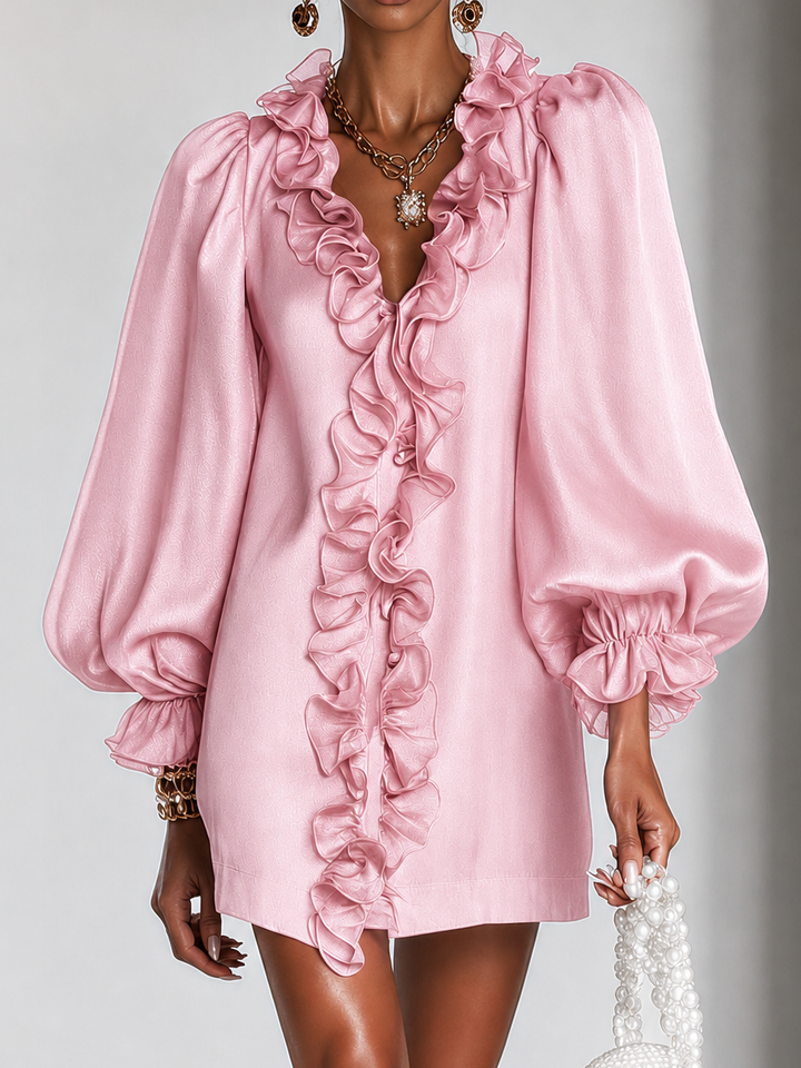 Gros plan sur le buste de la robe rose, volants en cascade sur le devant et manches bouffantes. 8
