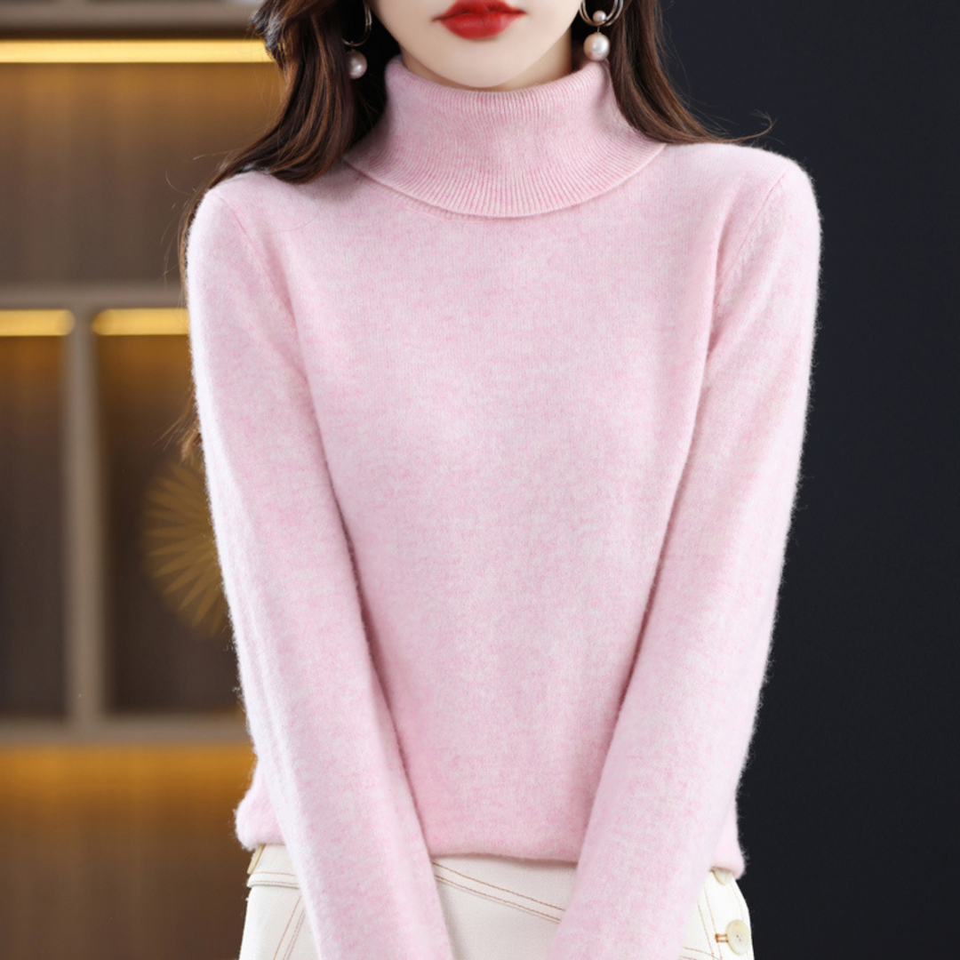 Pull rose pâle chiné à col roulé porté par une femme, vue de face avec une jupe blanche à boutons. 8