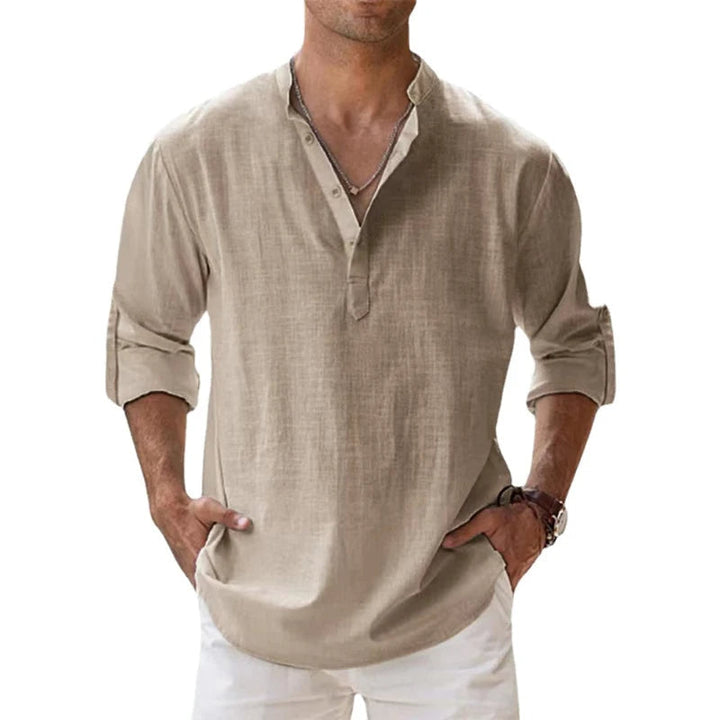 Homme portant la chemise Henley beige, manches retroussées, mains dans les poches d'un pantalon blanc, vue de face. 1