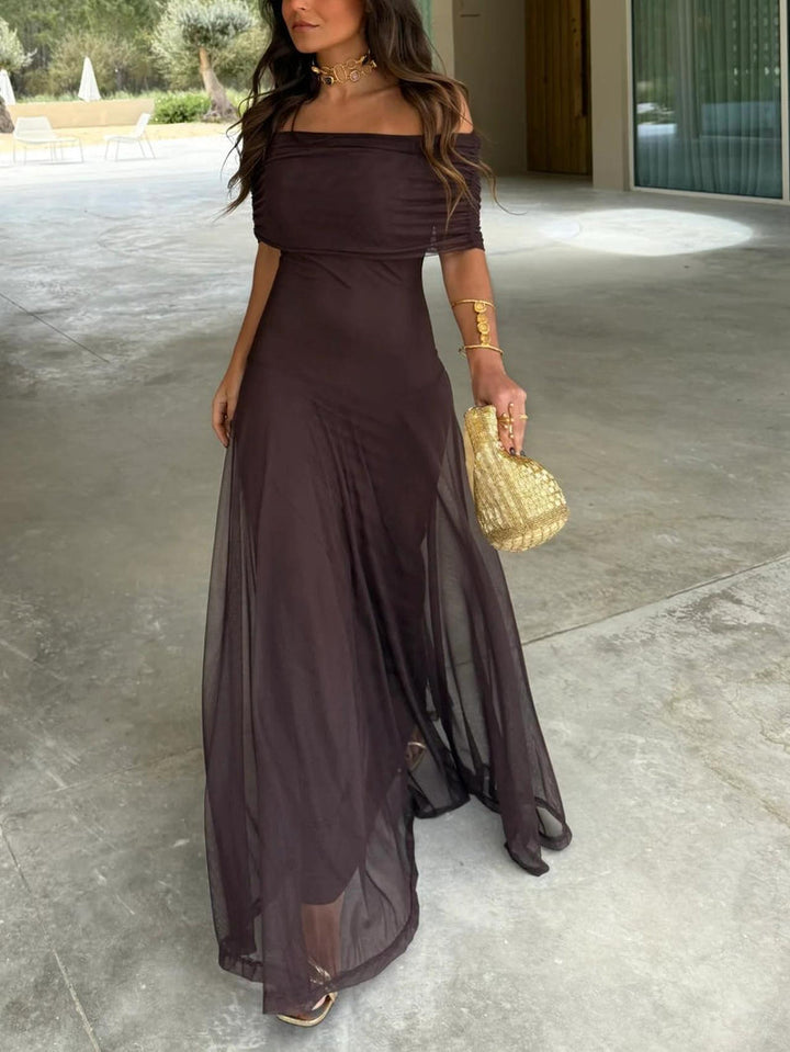 Robe maxi marron en maille transparente, épaules dénudées, portée de face avec pochette dorée 1