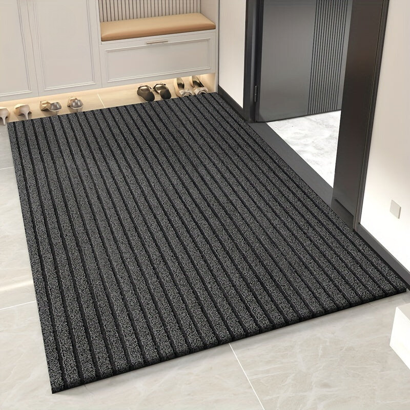 Tapis gris anthracite à rayures en relief posé dans une entrée, devant un banc et des chaussures rangées. 1