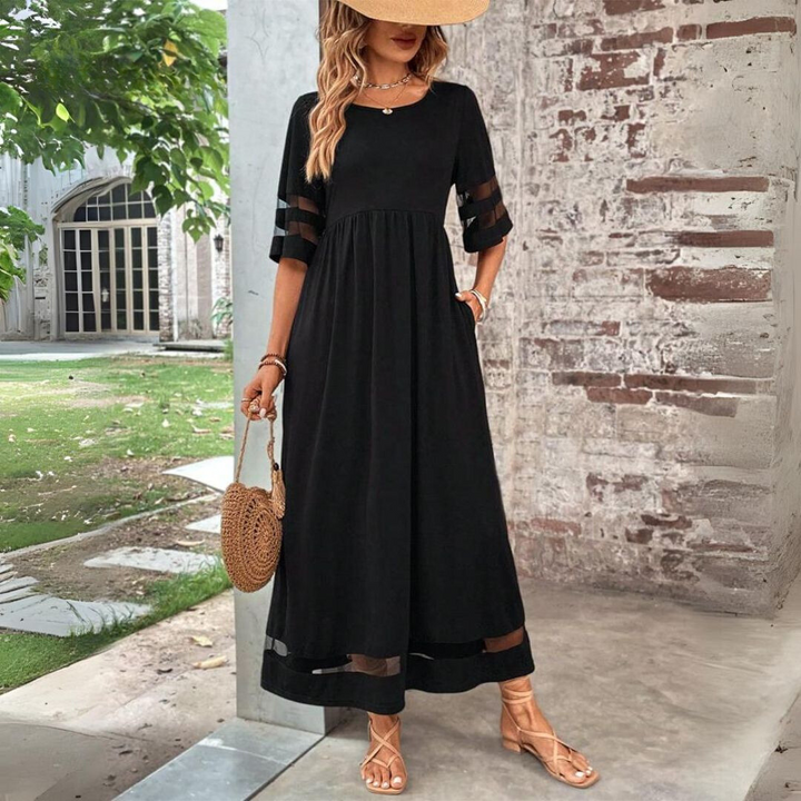 Robe longue noire à manches mi-longues et bandes transparentes, portée en extérieur avec chapeau de paille et sac rond en osier. 1