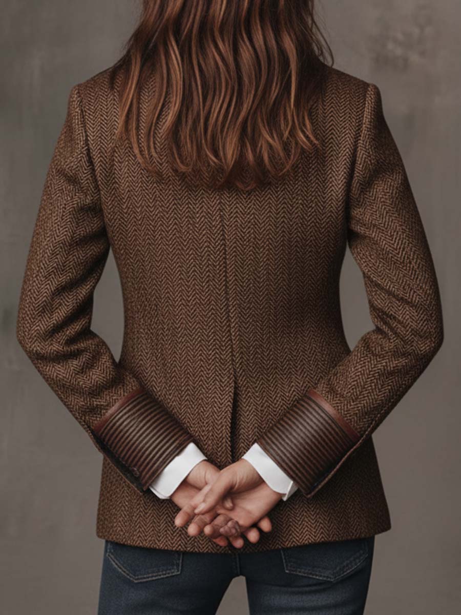 Dos du blazer, mains jointes derrière, manchettes rayées bordées de cuir relevées sur chemise blanche 11