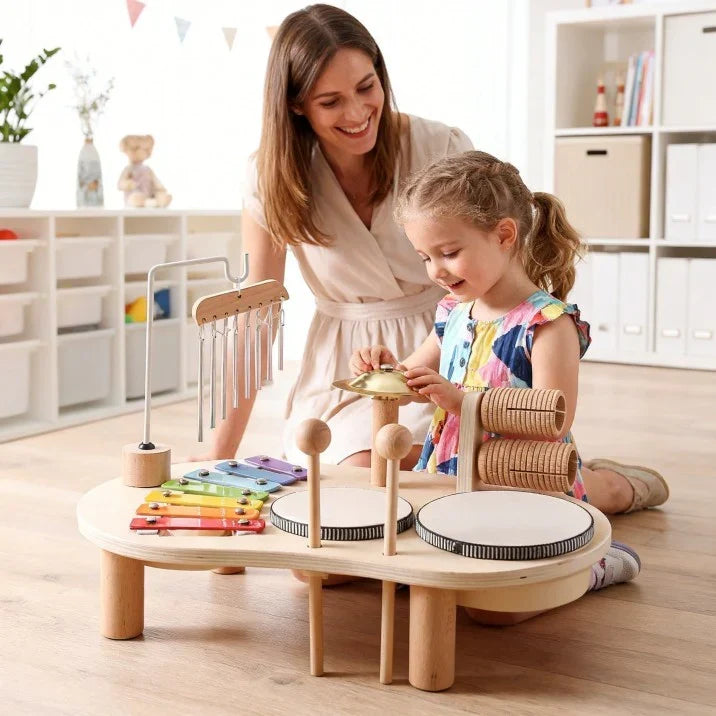 Une femme sourit en regardant une petite fille jouer de la cymbale sur la table musicale 5
