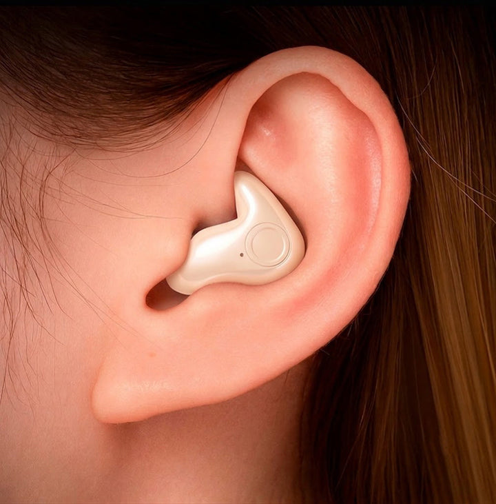 Gros plan d'une oreille portant un écouteur beige nacré à bouton circulaire 2