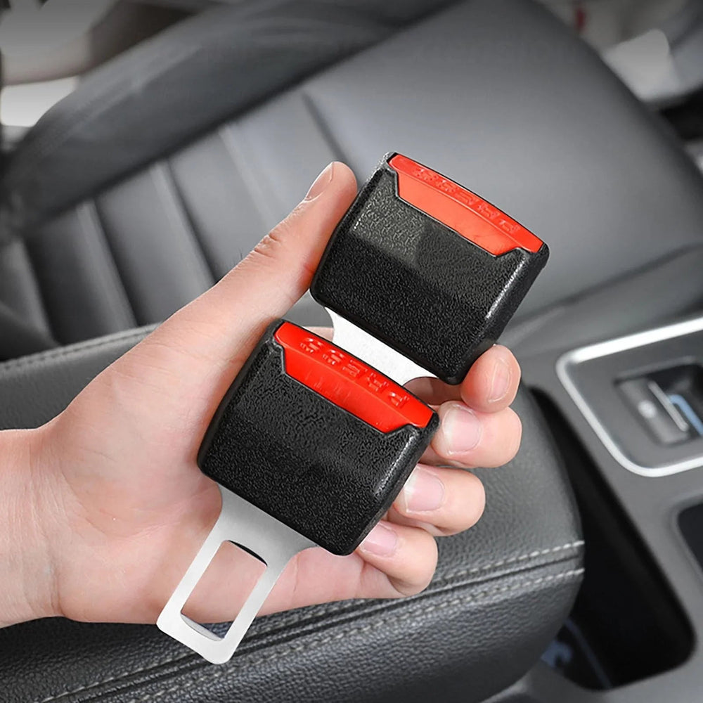 Deux inserts de boucle noirs à bouton rouge tenus dans une main, devant un siège de voiture 2