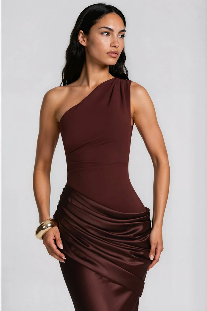 Gros plan sur le buste de la robe bordeaux foncé, épaule unique et drapé satiné à la taille, bracelet doré. 9
