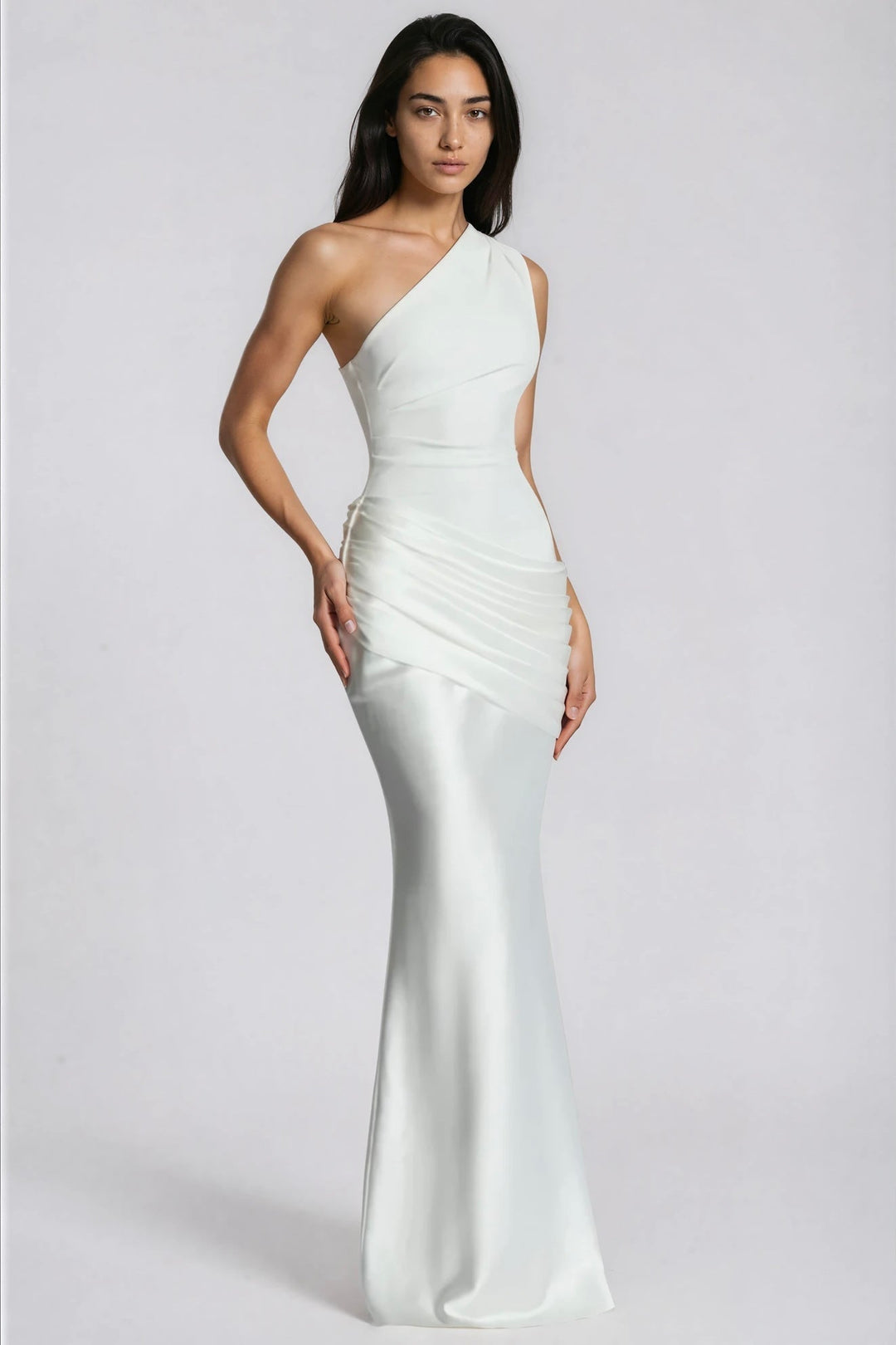 Robe longue blanche portée de trois quarts, main posée sur la hanche, drapé plissé en satin brillant. 11