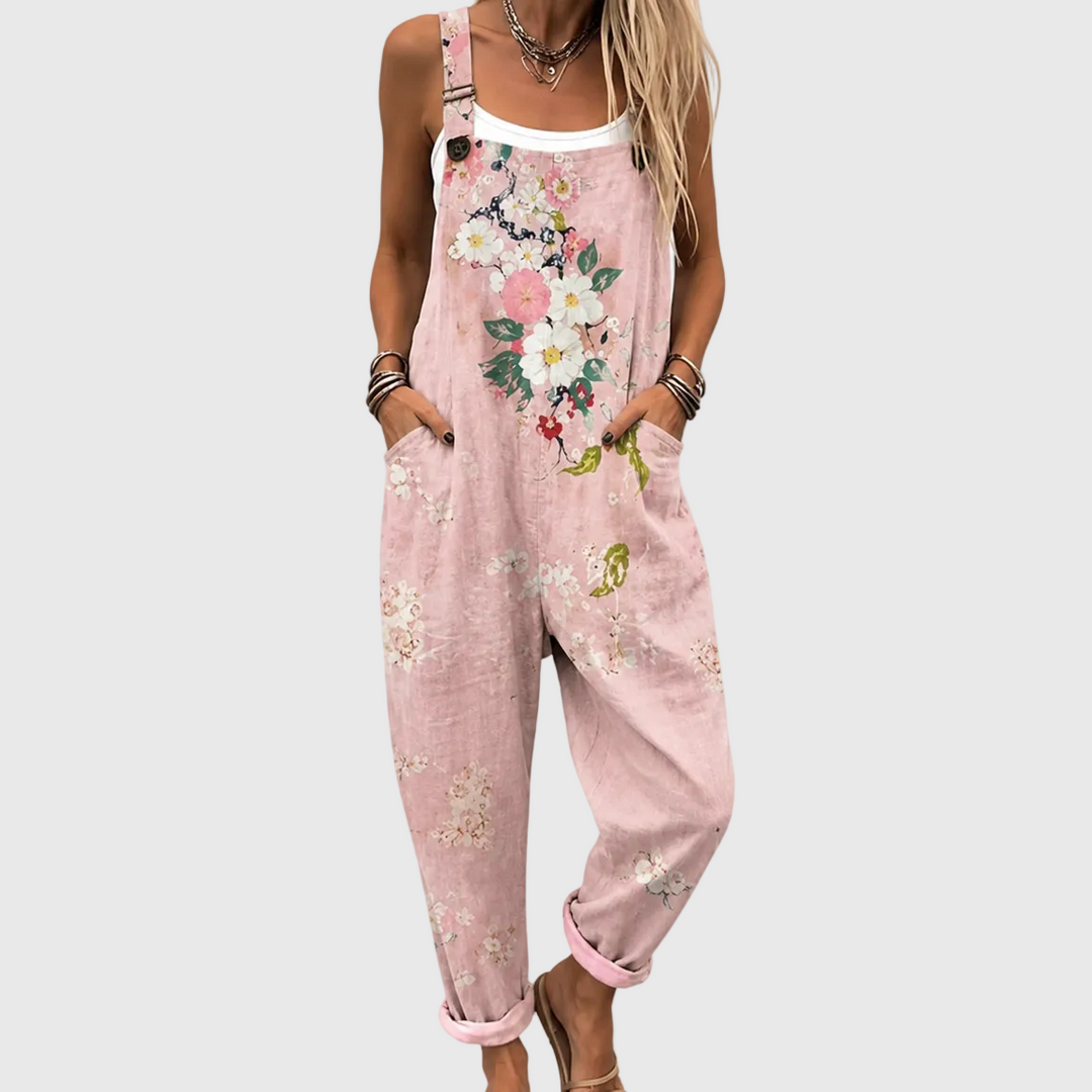 Gros plan sur le buste et les jambes d'une femme en salopette rose, mains dans les poches, bouquet de fleurs sur la bavette. 1