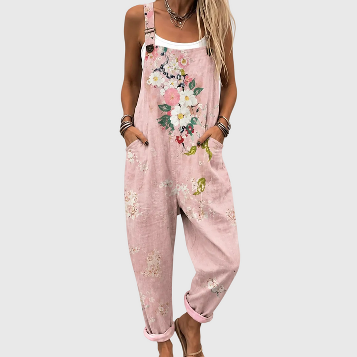 Gros plan sur le buste et les jambes d'une femme en salopette rose, mains dans les poches, bouquet de fleurs sur la bavette. 1