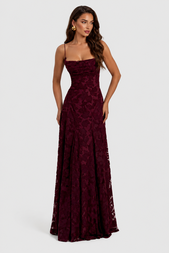 Robe bordeaux en dentelle florale, encolure drapée et fines bretelles, jupe longue fluide, portée de face par une mannequin aux boucles dorées. 20