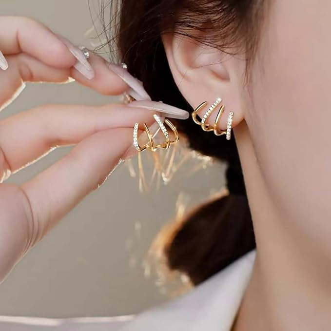 Gros plan d'une oreille ornée de la boucle à griffes dorées, l'autre pincée entre deux doigts 2