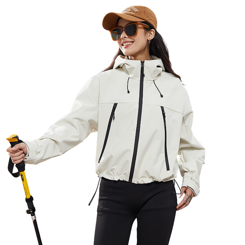 Femme souriante portant la veste écru avec casquette et lunettes, un bâton de marche jaune à la main, ourlet resserré par cordon. 3