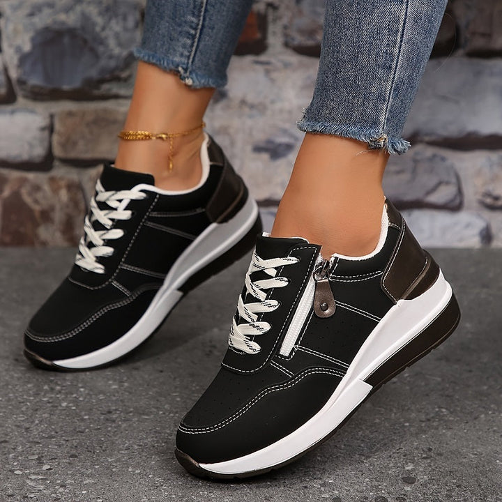 Baskets noires à surpiqûres blanches portées en marchant, zip latéral et lacets blancs bien visibles 4