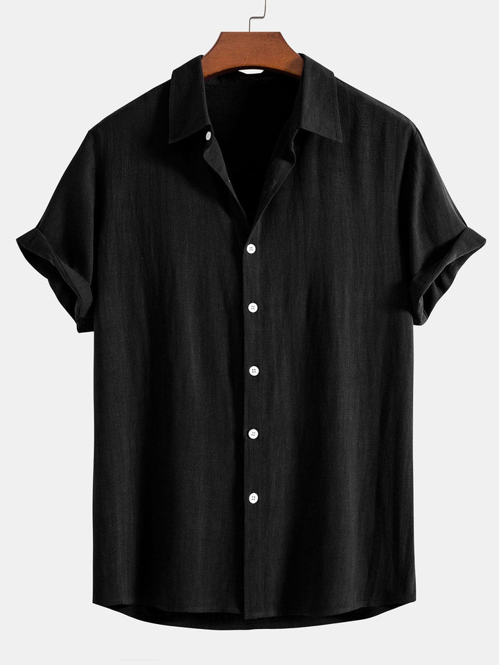 Chemise à manches courtes retroussées, coloris noir, sur cintre en bois, vue de face avec boutons blancs. 2