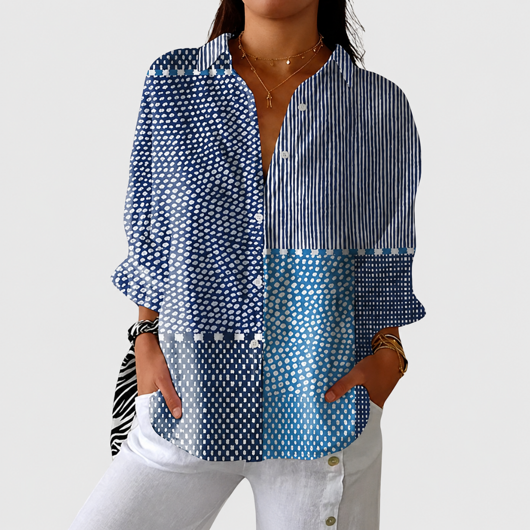 Femme portant la blouse boutonnée à blocs bleus rayés et pointillés, mains dans les poches d'un pantalon blanc 1
