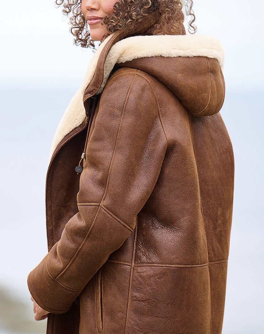 Vue de profil du manteau porté, montrant la capuche doublée de laine crème, la manche et la couture latérale. 2