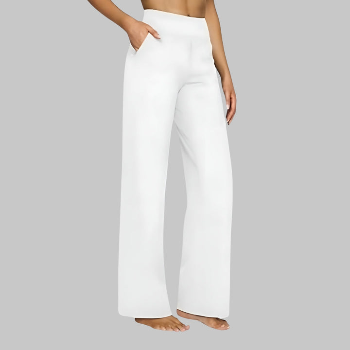 Pantalon blanc à jambe ample et taille haute, porté par une femme pieds nus, une main dans la poche. 8