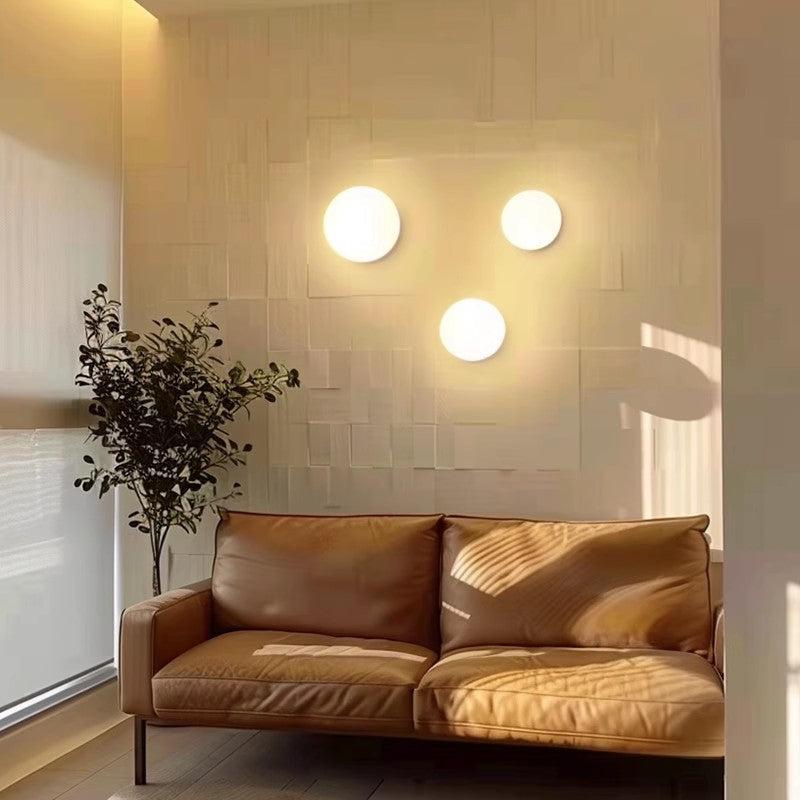 Trois sphères lumineuses disposées en triangle sur un mur texturé, au-dessus d'un canapé en cuir 13