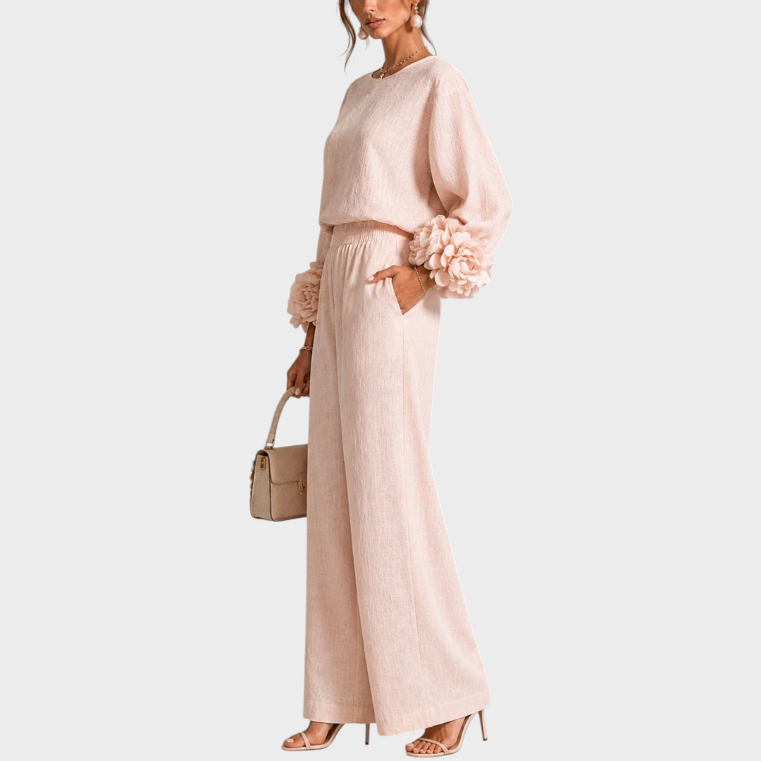 Ensemble rose pâle vu de trois quarts, main dans la poche, fleurs en relief sur les manches 9
