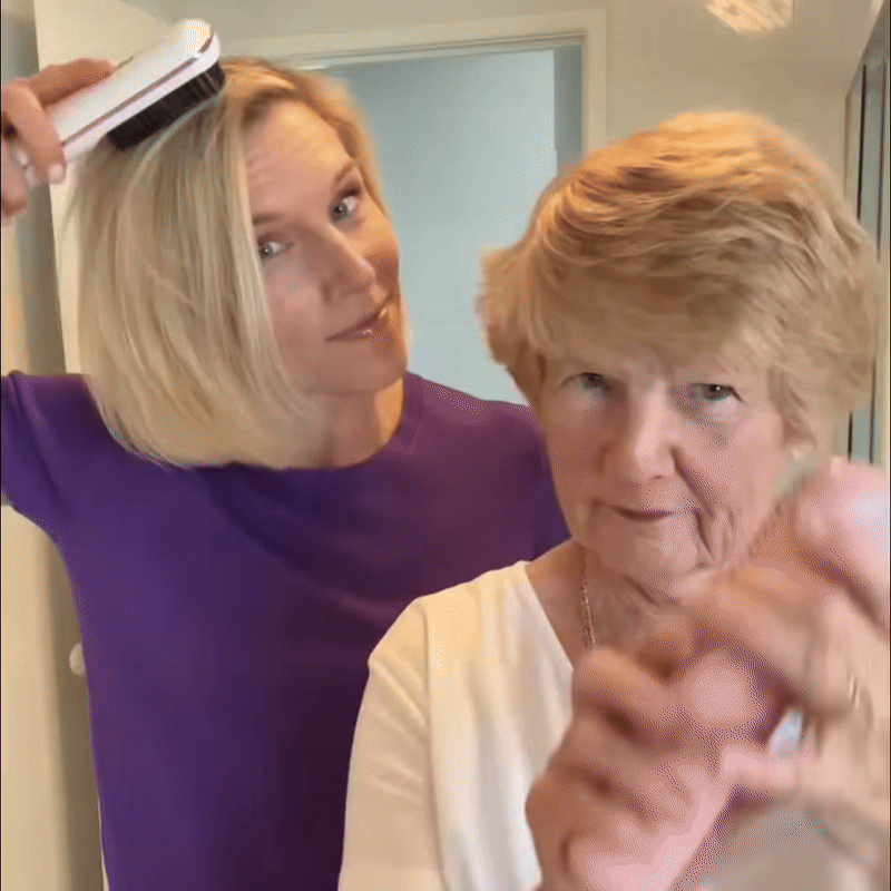 Femme en haut violet lissant ses cheveux blonds avec une brosse blanche à côté d'une femme âgée aux cheveux courts. 9