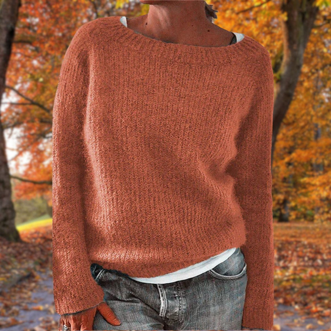 Pull en maille terracotta à col rond porté par une femme sur un t-shirt blanc, avec jean, dans un paysage d'automne. 6