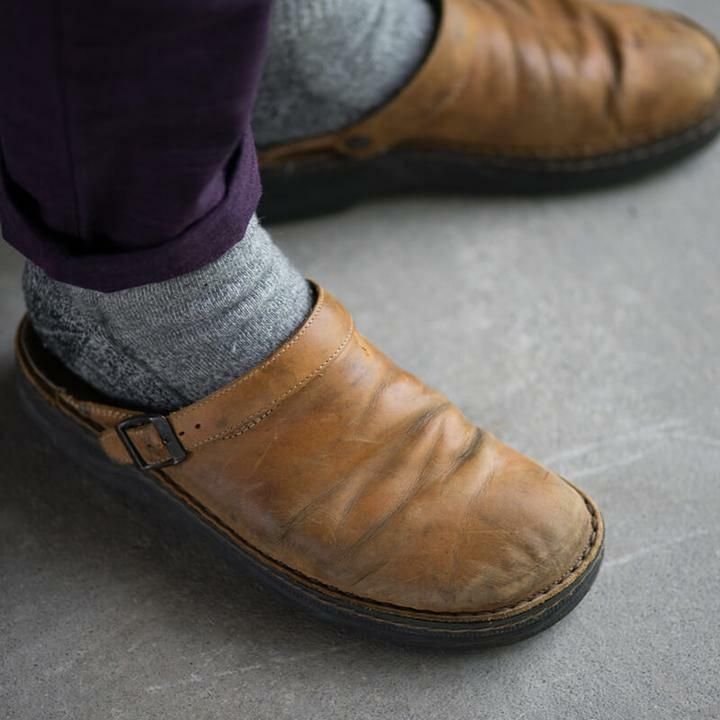 Pied porté d'une mule en cuir brun clair avec chaussette grise et pantalon violet 2