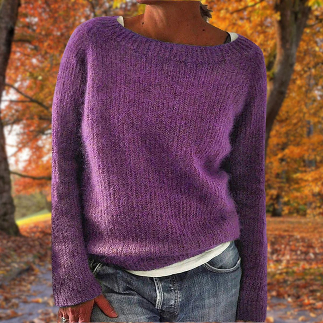 Pull en maille violet à col rond porté par une femme sur un t-shirt blanc, avec jean, dans un parc d'automne. 7