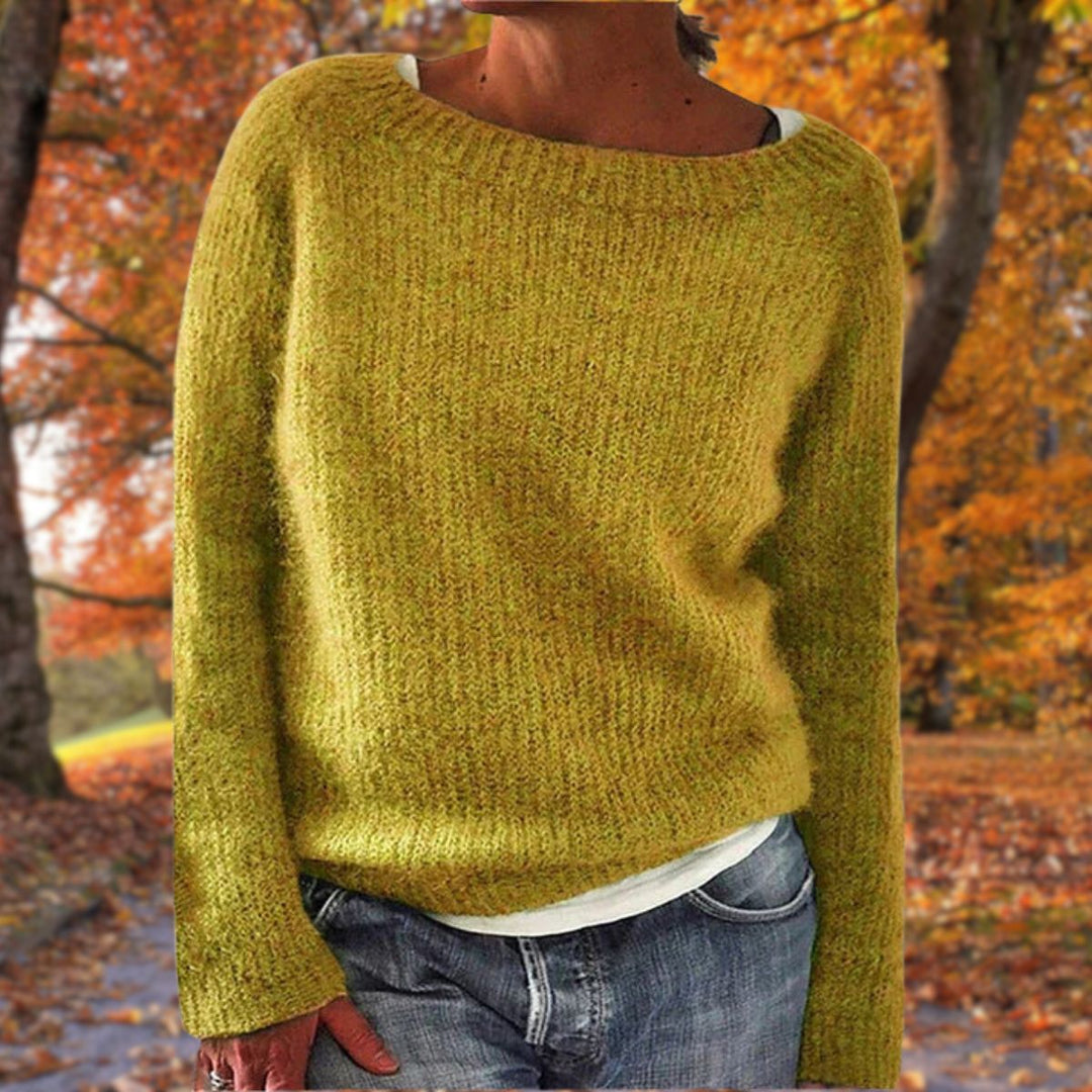 Pull en maille jaune moutarde à col rond porté par une femme sur un t-shirt blanc, avec jean, dans un parc d'automne. 1