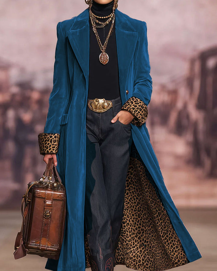 Manteau en velours bleu pétrole, même coupe longue et doublure léopard, porté avec pull noir, jean, ceinture dorée et sac en cuir marron. 6