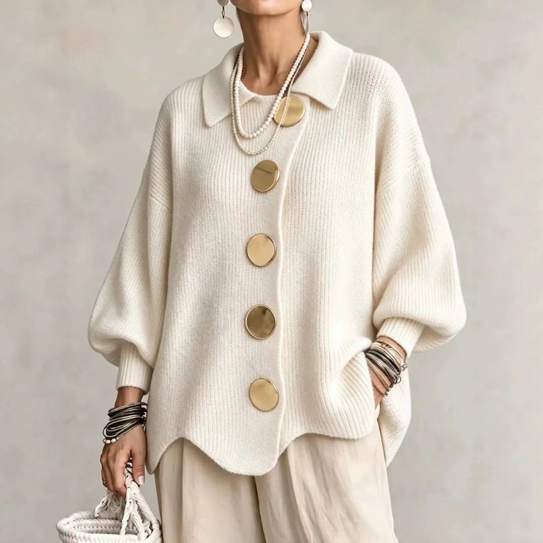 Cardigan blanc crème à col pointu et gros boutons dorés, porté avec un pantalon beige et des colliers de perles. 4
