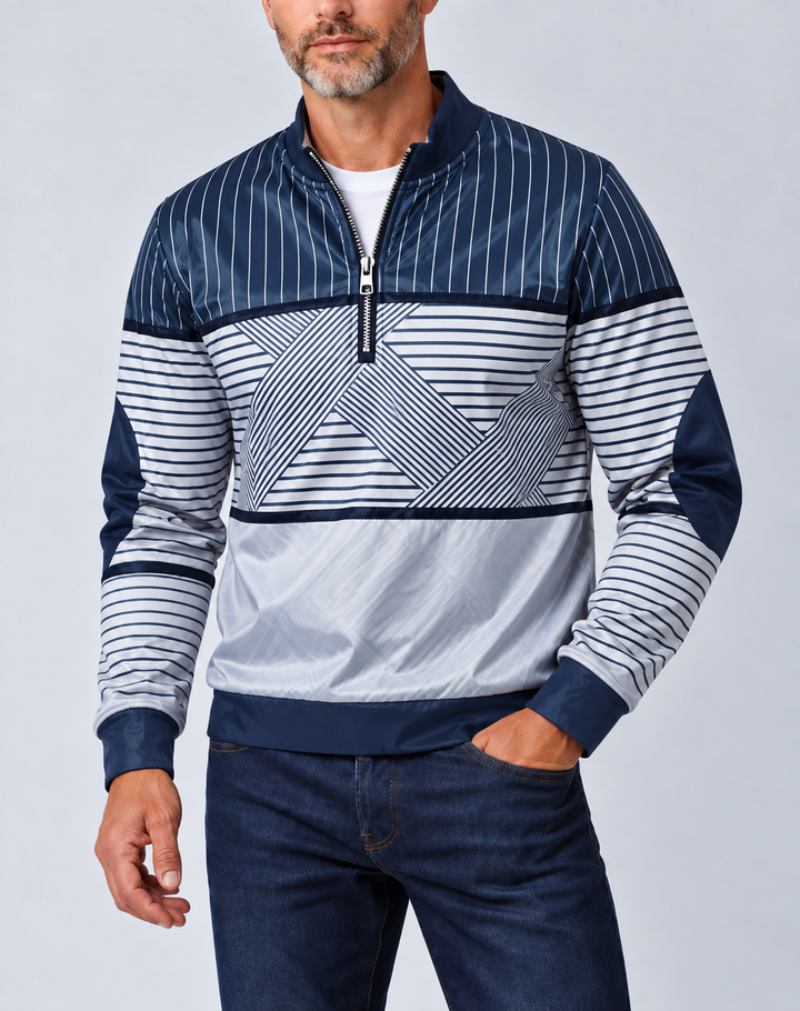 Homme barbu portant le pull bleu marine et blanc à demi-zip, col montant, sur un t-shirt blanc et un jean, vu de face. 1