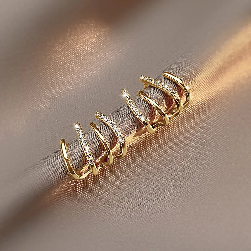 Paire de boucles à griffes en version dorée, posée sur un tissu satiné beige aux reflets chauds 7