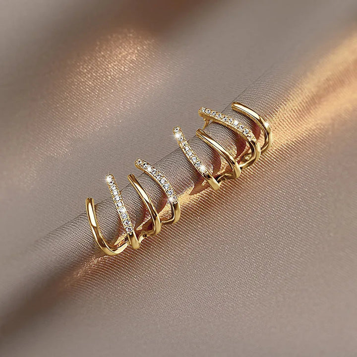 Paire de boucles à griffes en version dorée, posée sur un tissu satiné beige aux reflets chauds 7