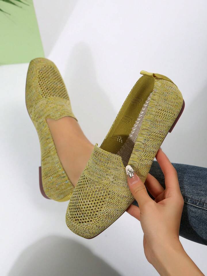 Soulier vert olive tenu à la main, laissant voir l'intérieur doublé et la semelle, l'autre chaussure portée en arrière-plan. 19