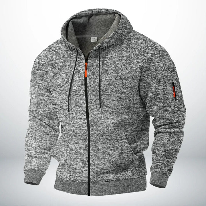 Sweat à capuche zippé en chiné gris clair, présenté de trois quarts, doublure grise visible dans la capuche et tirette orange. 3