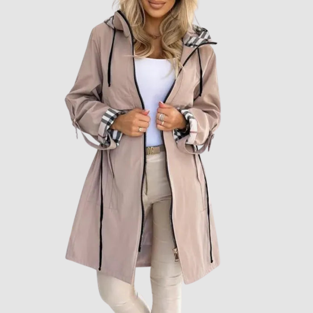 Femme portant le manteau beige rosé ouvert, manches retroussées montrant la doublure à carreaux, avec pantalon clair et haut blanc. 2