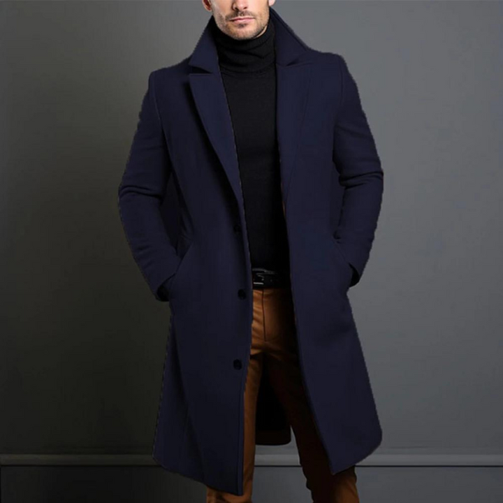 Manteau long en version bleu marine foncé, porté par un homme les mains dans les poches, col roulé noir. 4