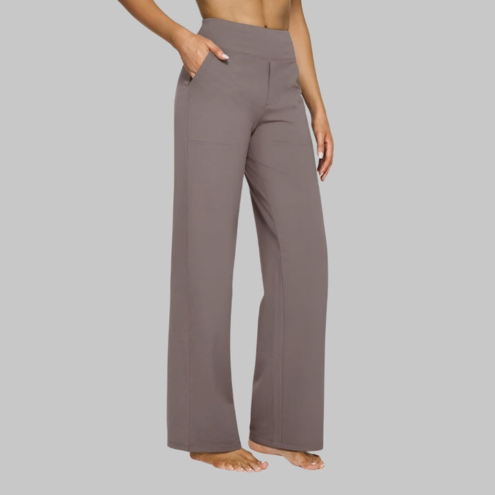 Pantalon taupe vu de trois quarts, porté par une femme pieds nus, une main dans la poche, jambe droite et taille haute. 1