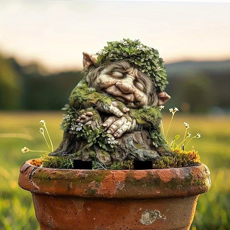 Tuteur du troll endormi à la couronne de feuilles, planté dans un pot en terre cuite usé, avec de petites fleurs blanches. 17