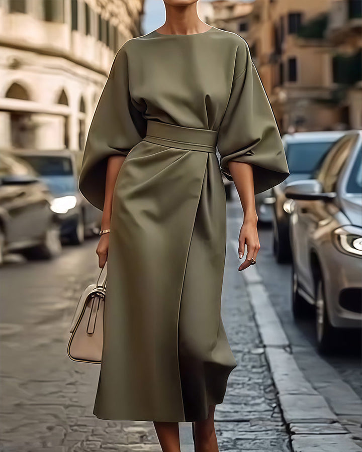 Robe vert kaki ceinturée à manches amples et jupe portefeuille drapée, portée dans une rue pavée avec un sac beige. 2