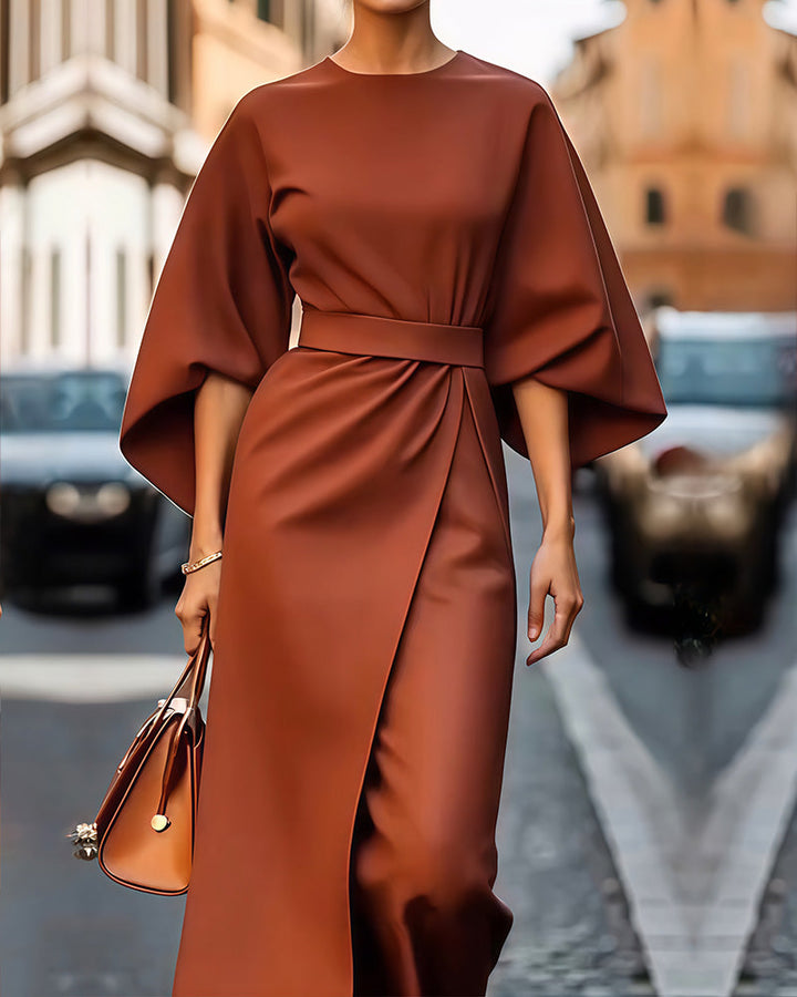 Robe terracotta ceinturée à larges manches et jupe portefeuille, portée en plan rapproché avec un sac à main marron clair. 3