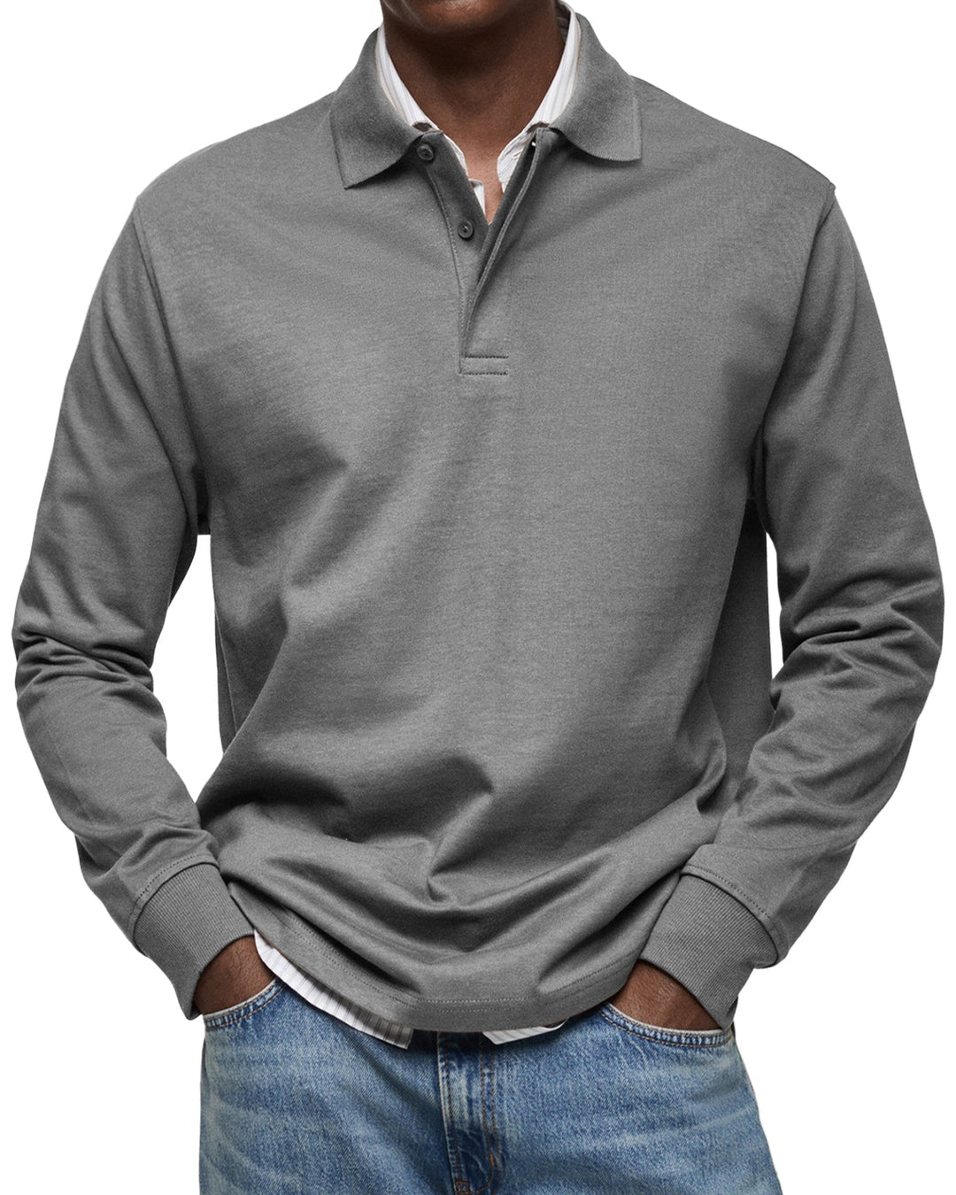 Polo à manches longues gris moyen porté par un homme, mains dans les poches, poignets côtelés, chemise rayée dessous et jean. 6